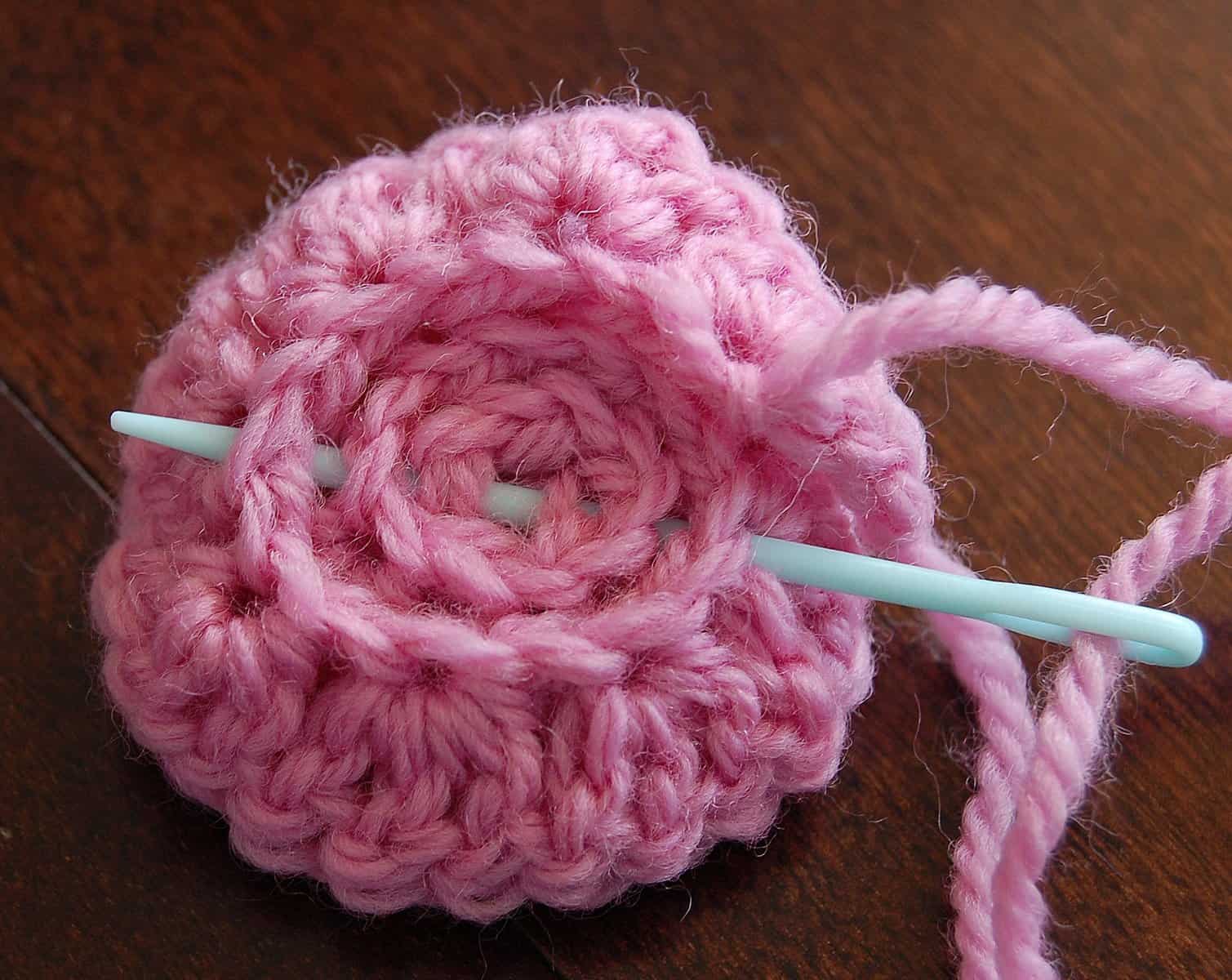 Use a yarn needle and tail of yarn to sew the rounds of the crochet rose together.