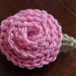 Medium pink crochet rose with small green leaf.