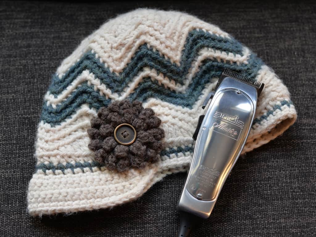 Chevron crochet newsboy hat with brown flower laying with electric clippers.