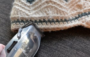 Metal clippers shaving off fuzzy yarn from crochet newsboy hat.