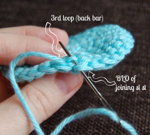 Yarn needle weaving in back loop and back bar to complete crochet invisible join.