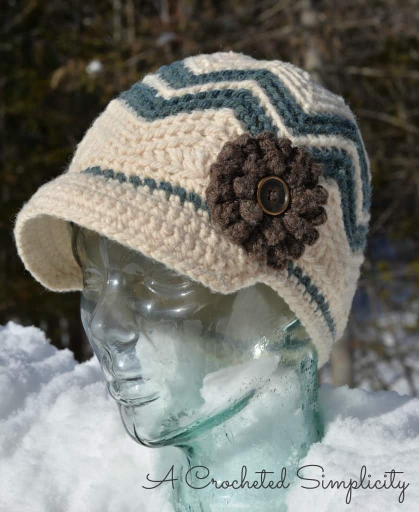 Cream and hunter green chevron crochet newsboy hat on glass mannequin head.