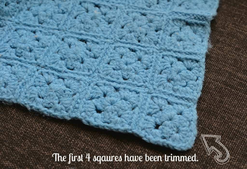 Light blue granny square blanket laying on brown chair.