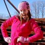 Girl winking while modeling pink ribbed crochet head warmer.