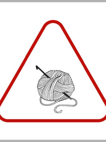 Red triangle with ball of yarn and crochet hook clipart in center.