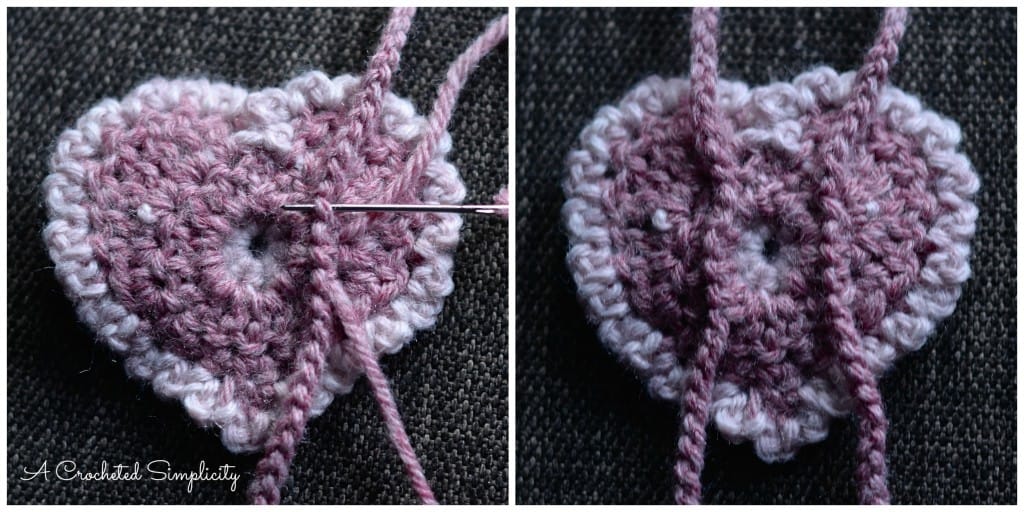 Yarn needle attaching crochet chains to back of pink heart.