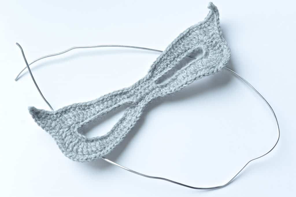 Grey crochet mask and piece of silver wire.