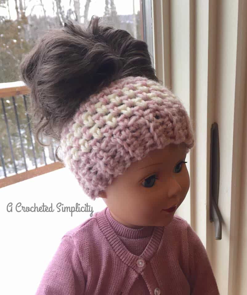 18" doll wearing a crochet ponytail hat in pink and cream