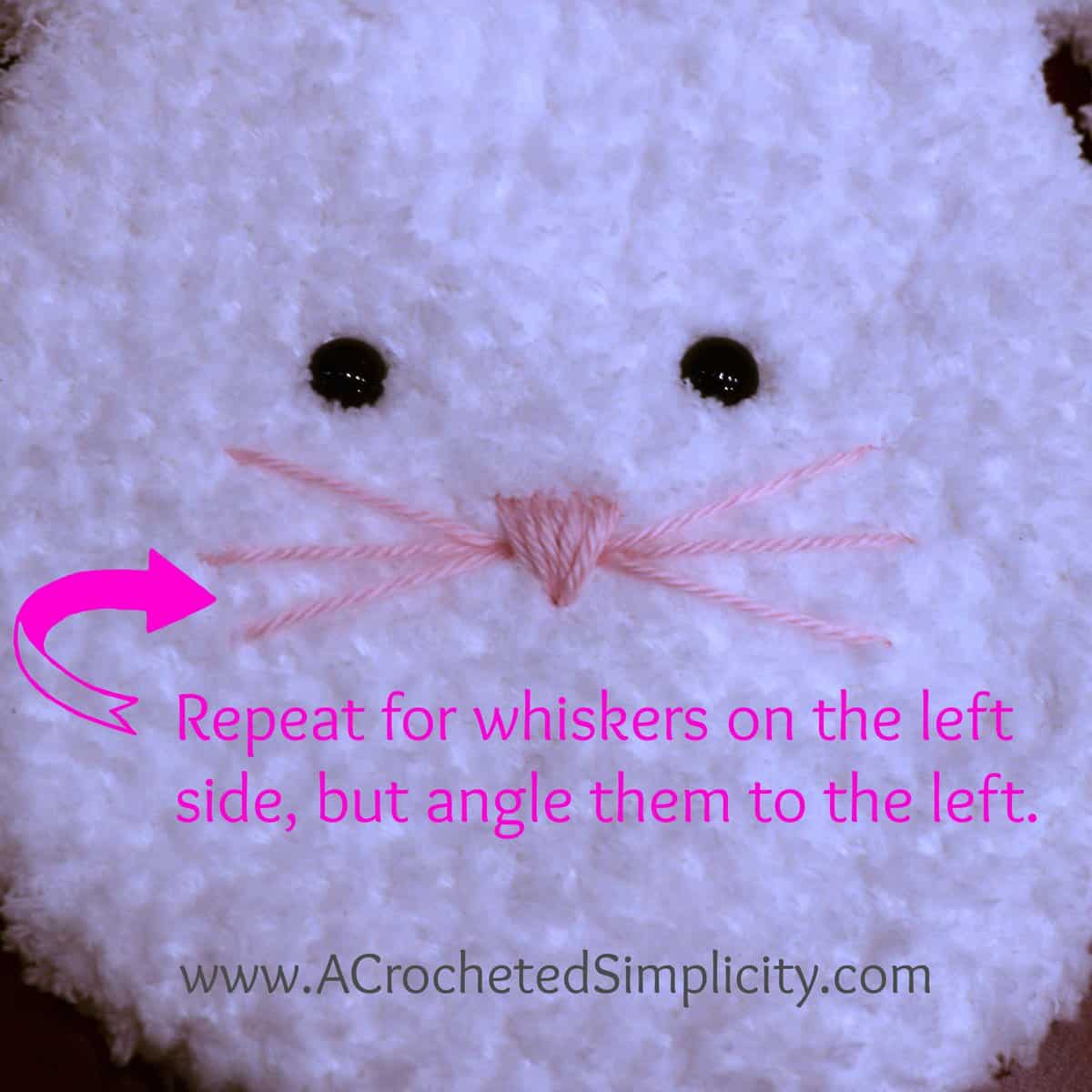 Crochet bunny face with a pink nose and pink whiskers.