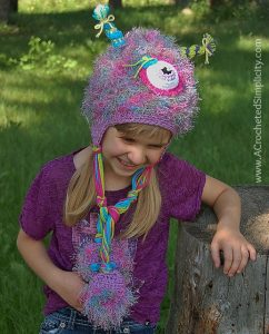 Girl modeling pink and purple crochet monster hat outside.