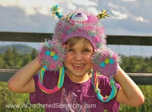 Young girl modeling pink and purple crochet monster hat with furry feet.