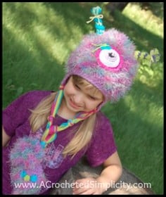 Pink and purple crochet monster hat with large eyeball modeled by young girl.