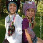 Boy and girl modeling crochet monster hats outdoors.