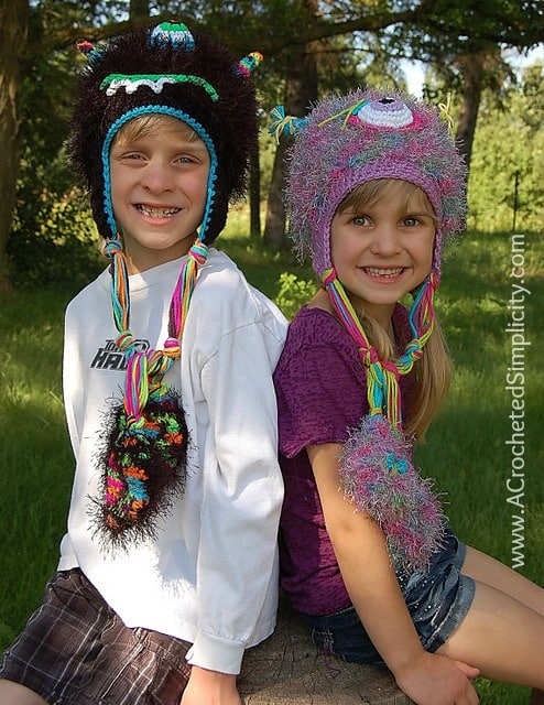 Boy and girl modeling crochet monster hats outdoors.
