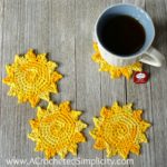 Sun shaped crochet coasters sitting on table with hot tea.