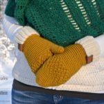 Cream and gold crochet mittens pattern modeled by woman outside in snow