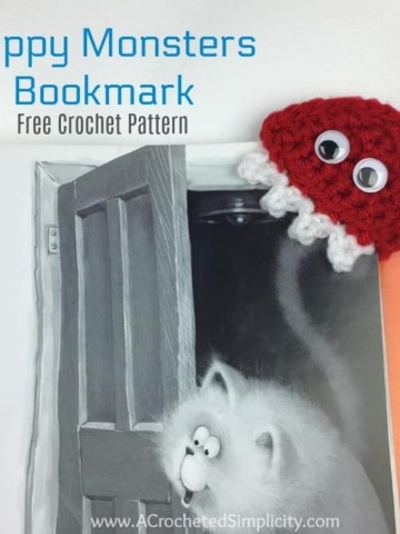 Red crochet monster bookmark on cat book.