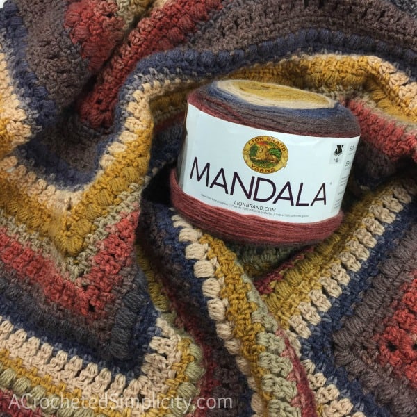 A cake of Lion Brand Mandala yarn against a crochet poncho.