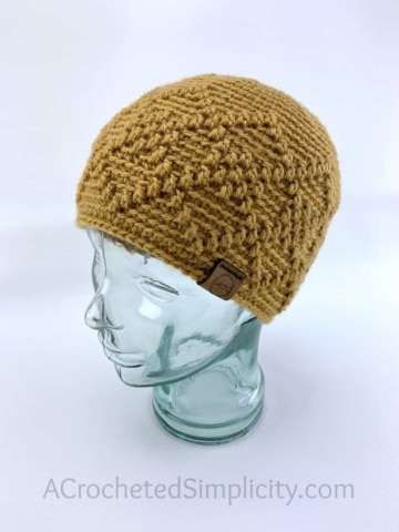 gold argyle messy bun hat on glass head stand