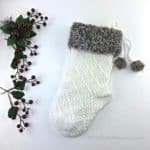 white Christmas crochet stocking with brown fur cuff laying on white background