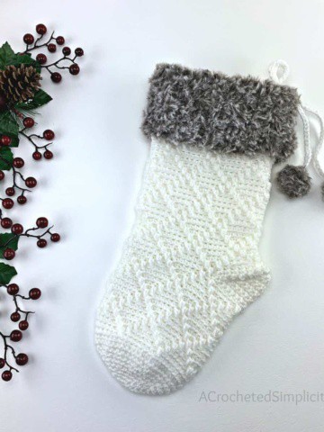 white Christmas crochet stocking with brown fur cuff laying on white background