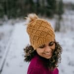 Embossed crochet diamond design hat in gold with faux fur pom.