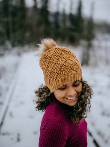 Embossed crochet diamond design hat in gold with faux fur pom.