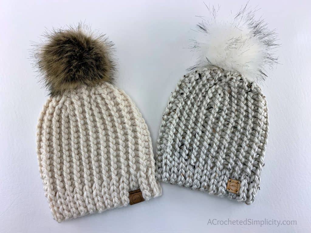 Two knit look crochet short row hats with faux fur poms.