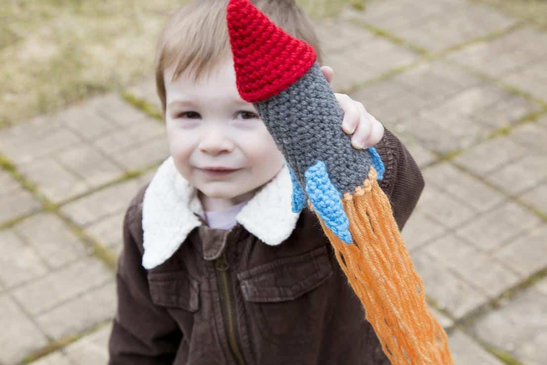 Small boy holding a crochet rocket amigurumi.