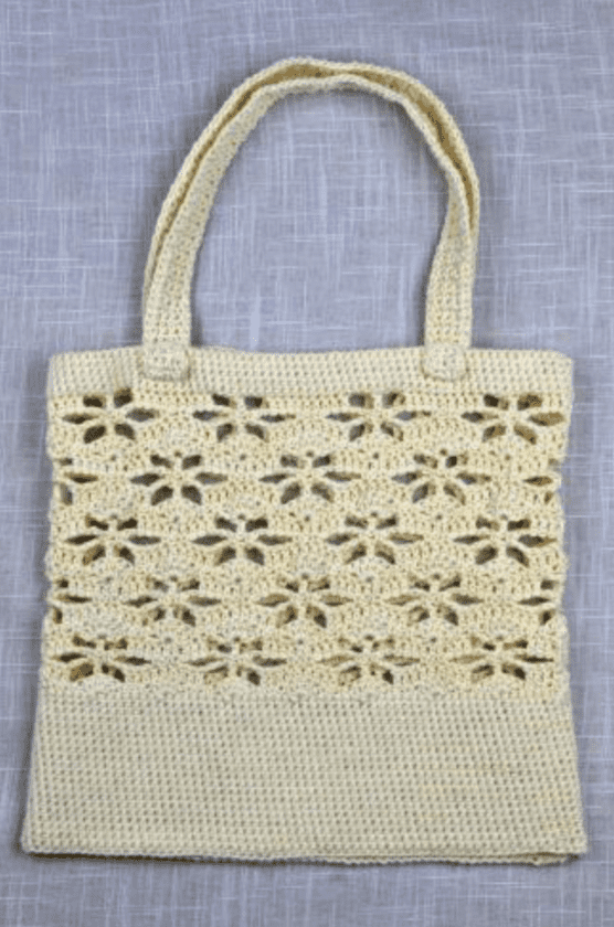 Ecru crochet tote bag laid flat on fabric surface.