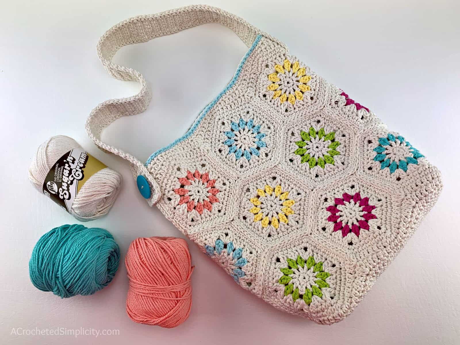 Cream colored hexagon motif crochet tote bag with bright color accents and cotton yarn.