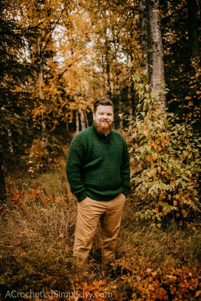 A man wearing a green crochet pullover sweater.