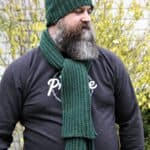 Man with beard wearing a green ribbed crochet scarf and beanie set.