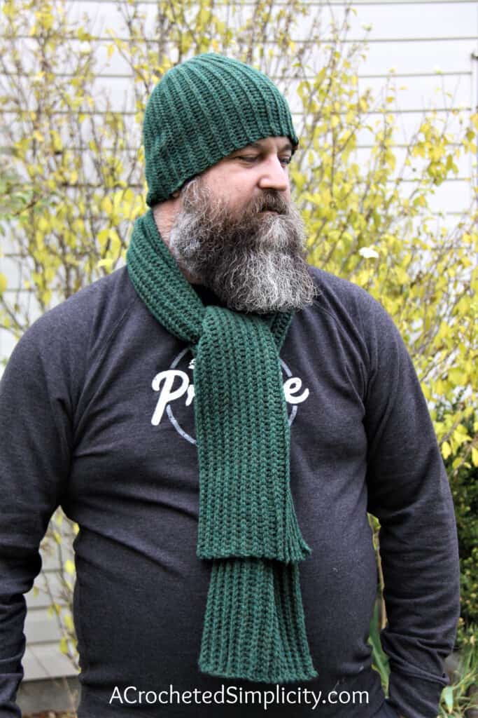 Man with beard wearing a green ribbed crochet scarf and beanie set.