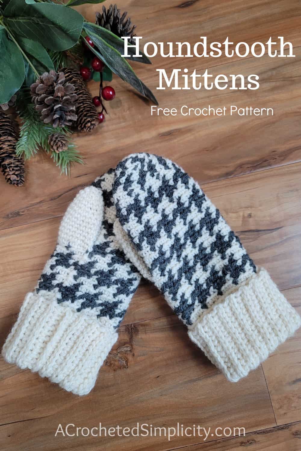 Charcoal grey and cream houndstooth crochet mittens laying on wood surface.