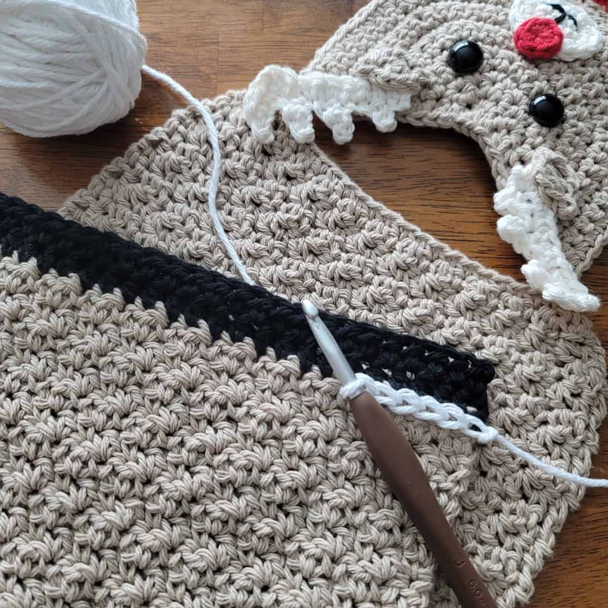 Outlining crochet reindeer hooves with white surface crochet stitches.