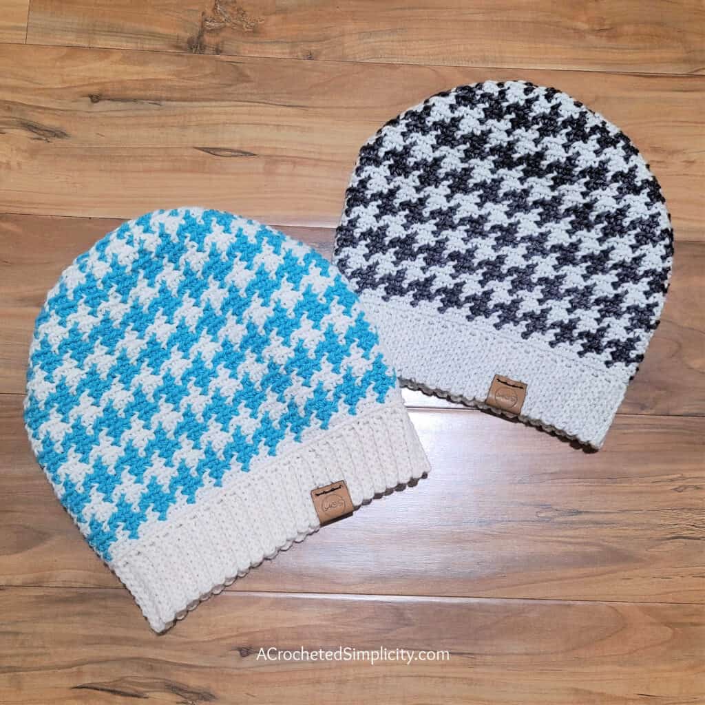 Two crochet houndstooth slouch hats laying on one floor.