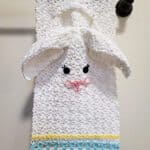 Cute crochet bunny towel and washcloth set hanging on towel bar.