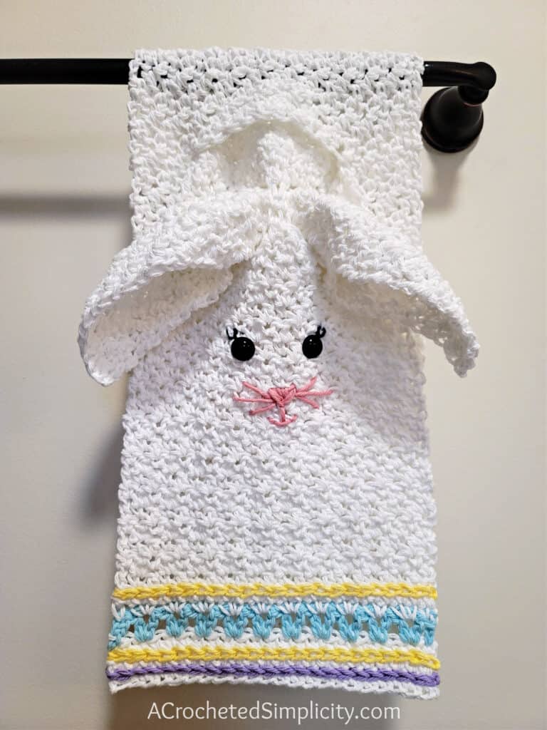 Cute crochet bunny towel and washcloth set hanging on towel bar.