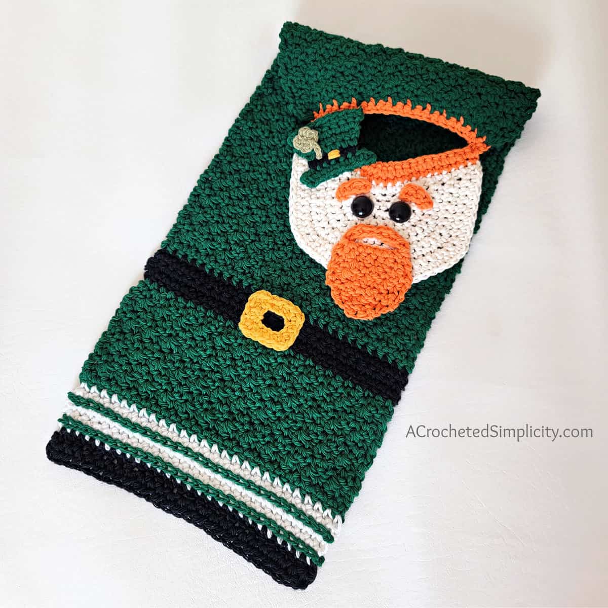 Crochet leprechaun hand towel laid flat on counter.