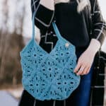 Close up of woman holding blueish green crochet market tote.