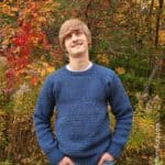 Young man modeling a blue crew neck crochet pullover.