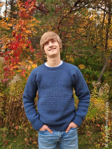 Young man modeling a blue crew neck crochet pullover.