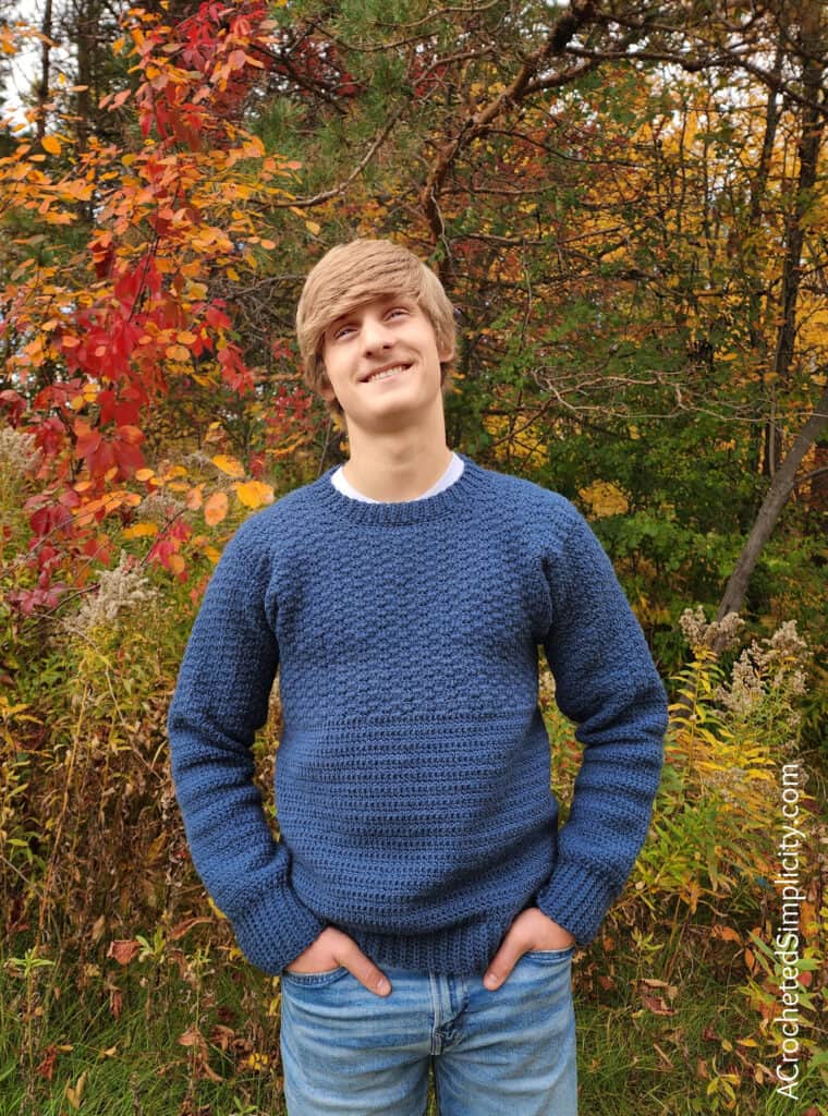 Young man modeling a blue crew neck crochet pullover.