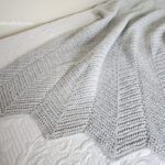 Light grey Herringbone Single Crochet Ripple Stitch Blanket on bed.