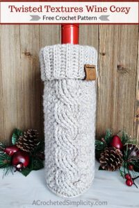 A taupe crochet wine cozy with a cable and ribbed cuff holding a bottle of wine.