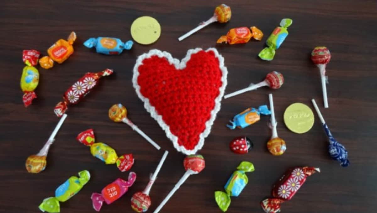 Red 3D crochet heart laying on a desk with candy.