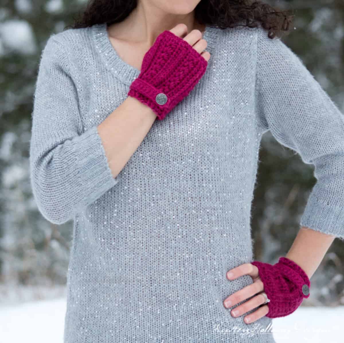 Woman in silver colored sweater wearing fuscia colored crochet fingerless mitts.