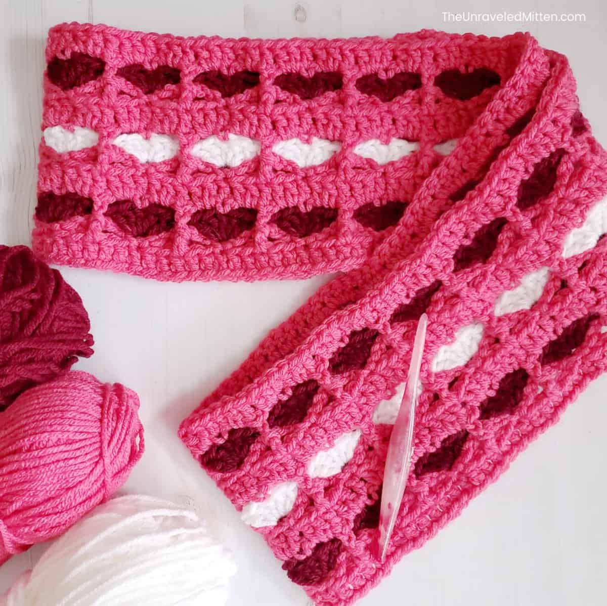 Bubblegum pink crochet infinity scarf with red and white hearts stitched in.