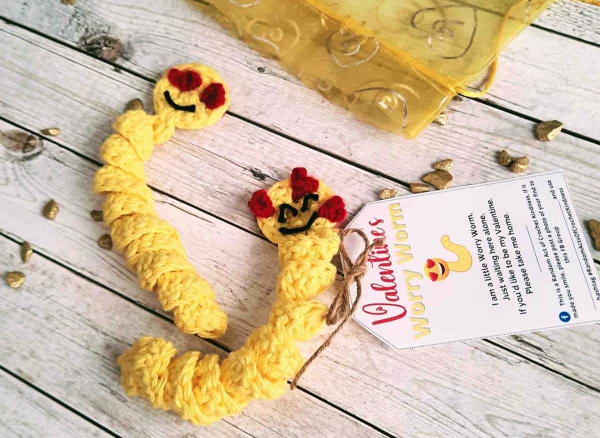 Yellow crochet worry worms with heart emoji eyes.